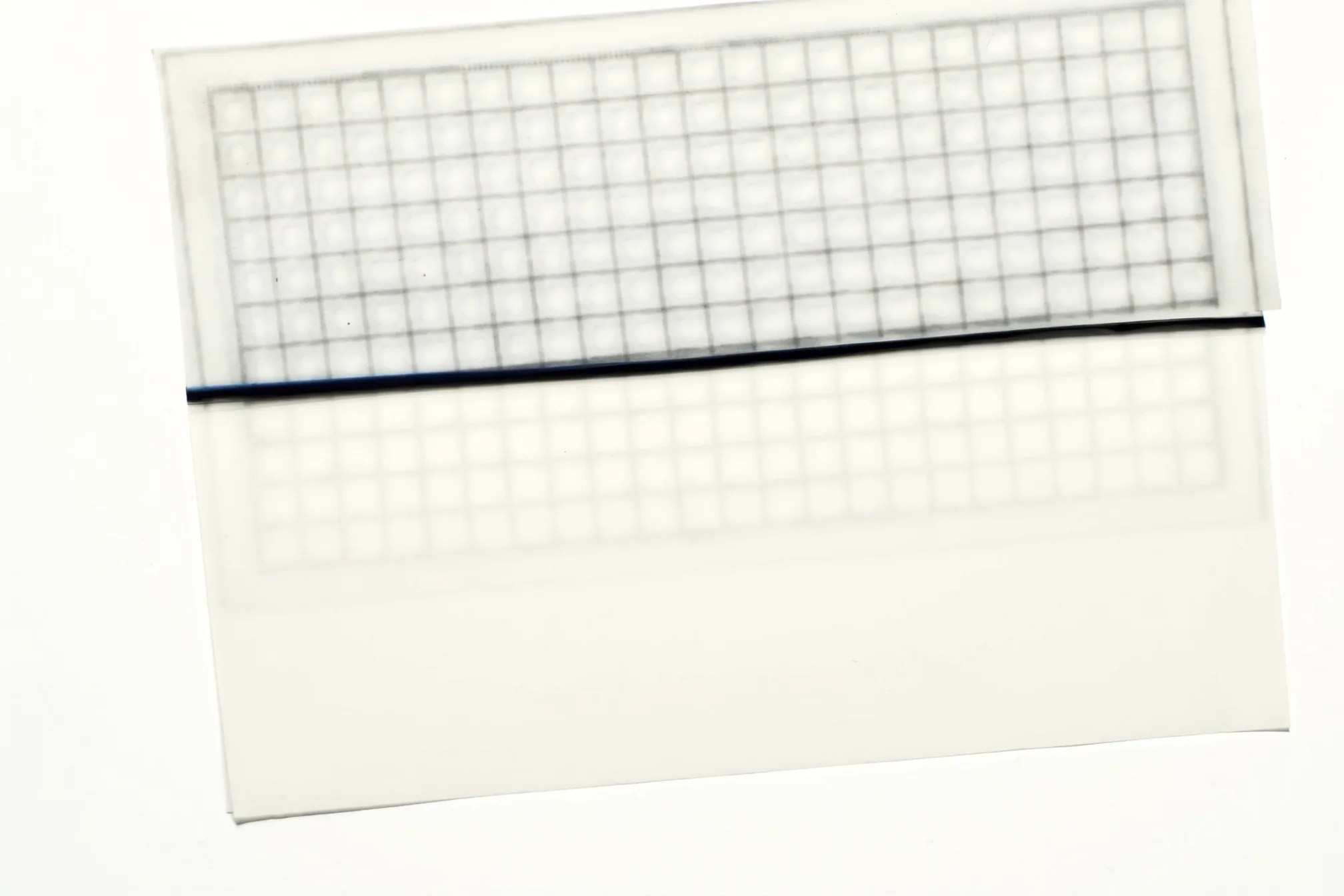Two translucent grid printed sheets overlapping on white paper, with a navy line across the middle.
